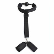 Accessorio BDSM nero ball-gag con polsiere collegate su sfondo bianco