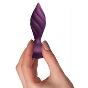Dimensioni reali plug anale Desire viola a spirale tenuto tra le dita su sfondo bianco